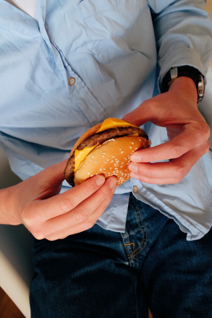 individual holding a cheeseburger