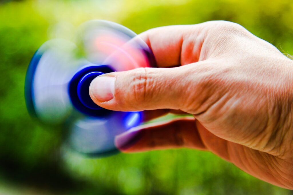 An individual is playing with a blue spinner which is an anxiety relief toy.