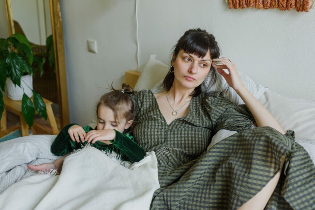 A Mother sitting next to her child looking off in the distance and wondering is feeling overwhelming as a parent all the time is normal.