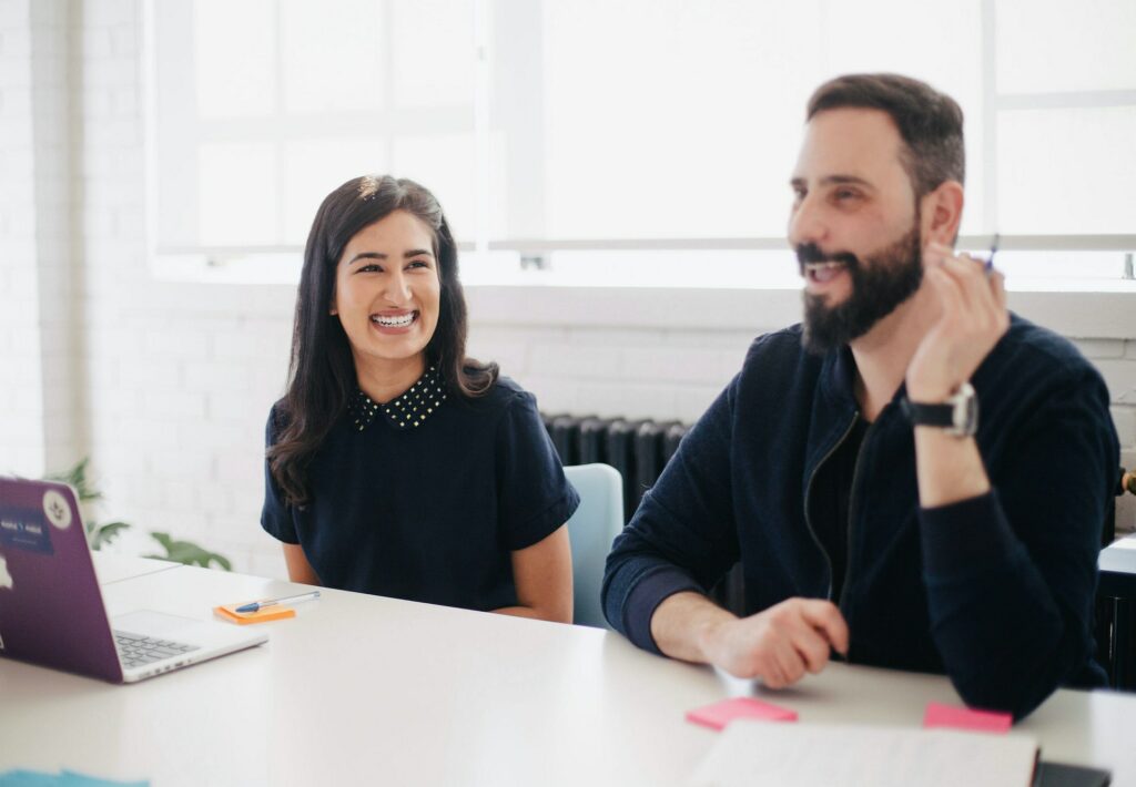 Smiling co-workers looking at work frustration quotes on comuter.