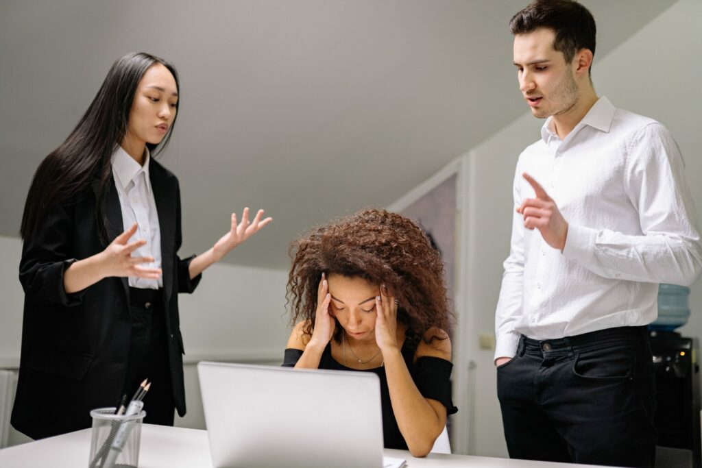 Young woman holding her head in her hands clearly overwhelmed at work.