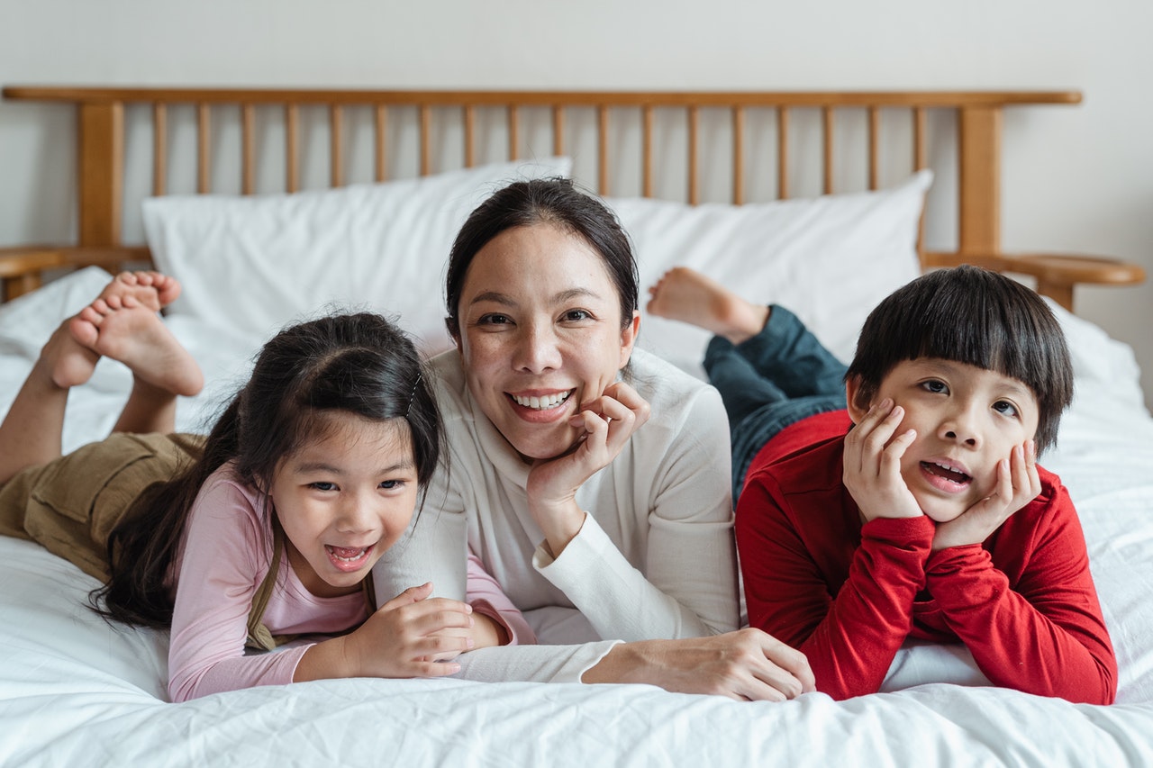 Smiling mom, son and daughter laying together on bed.