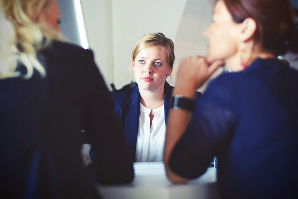 Woman with poor coping skills looking at anxious sitting with two co-worker.