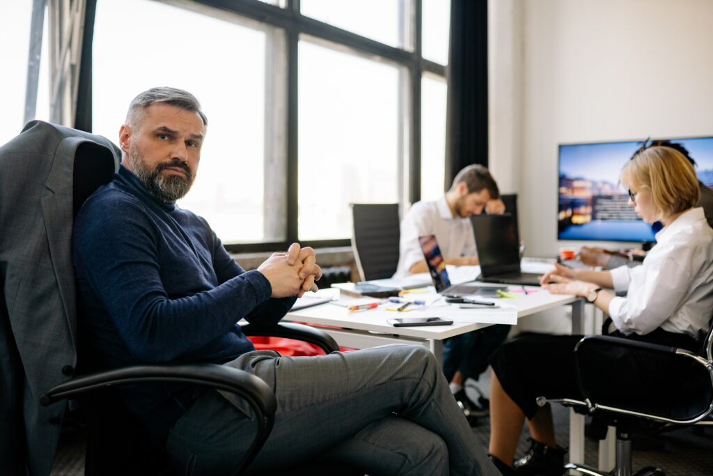 Businessman sitting with co-workers looking perplexed as to how to cope with stress at work.