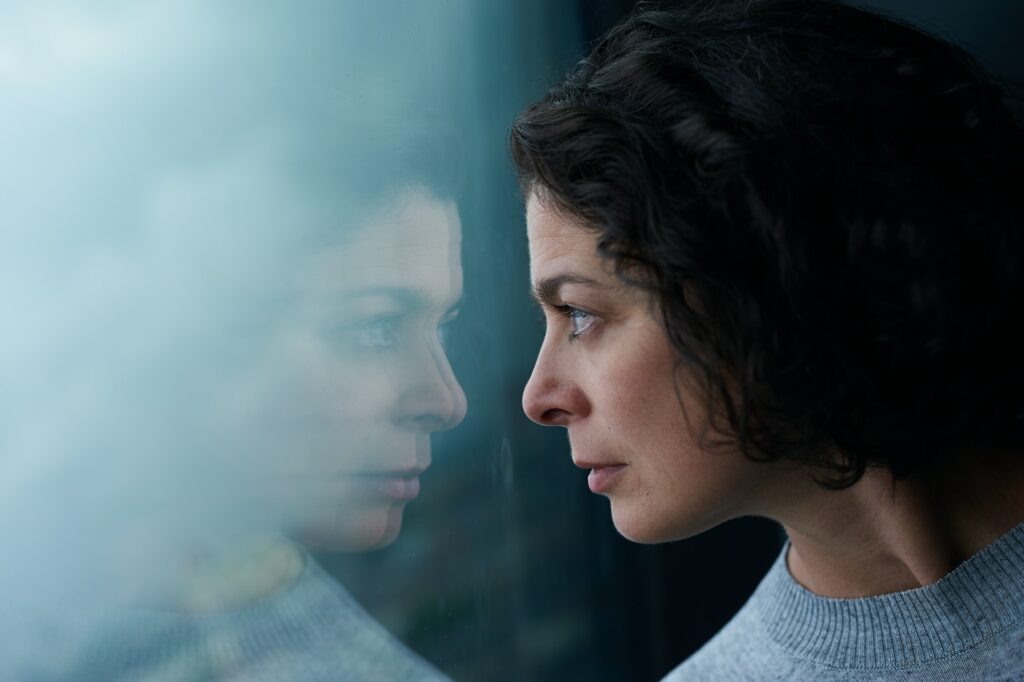 Anxious looking woman looking at her reflection and wondering what is the best remedy for anxiety