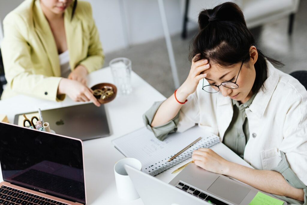 Frustrated woman sitting at desk trying to cope with stress at work.