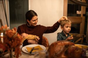 Woman sitting at Thanksgiving dinner table and practicing gratitude to calm down anxiety.