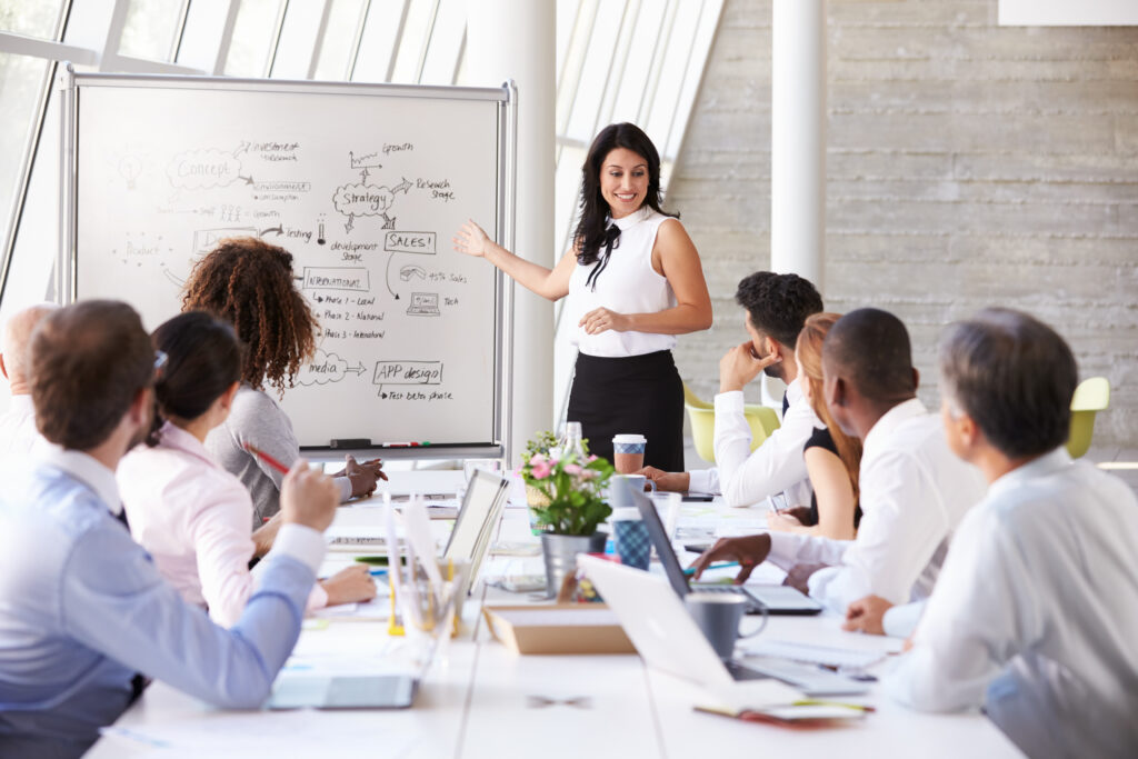 Hispanic Businesswoman Leading Meeting At Boardroom Table