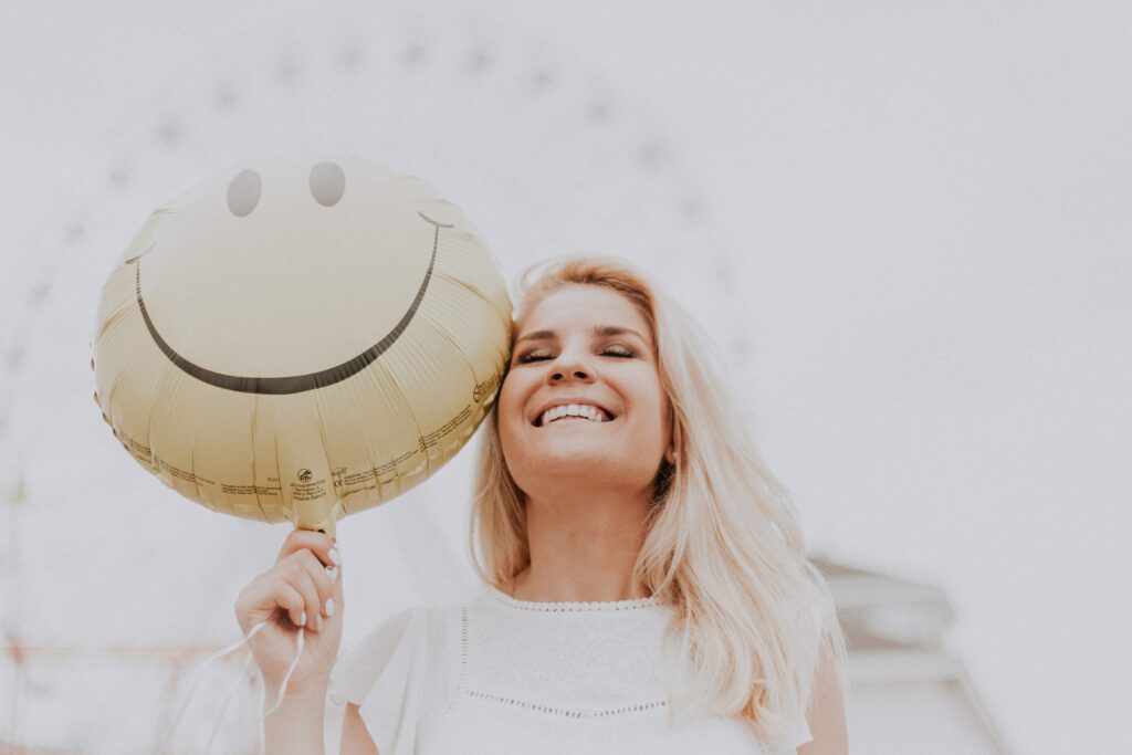 Smiling woman holding smiling face balloon