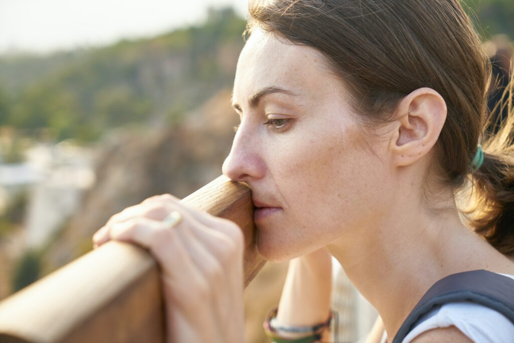 Distressed woman looking down over a brown rail trying to cope with the unexpected.