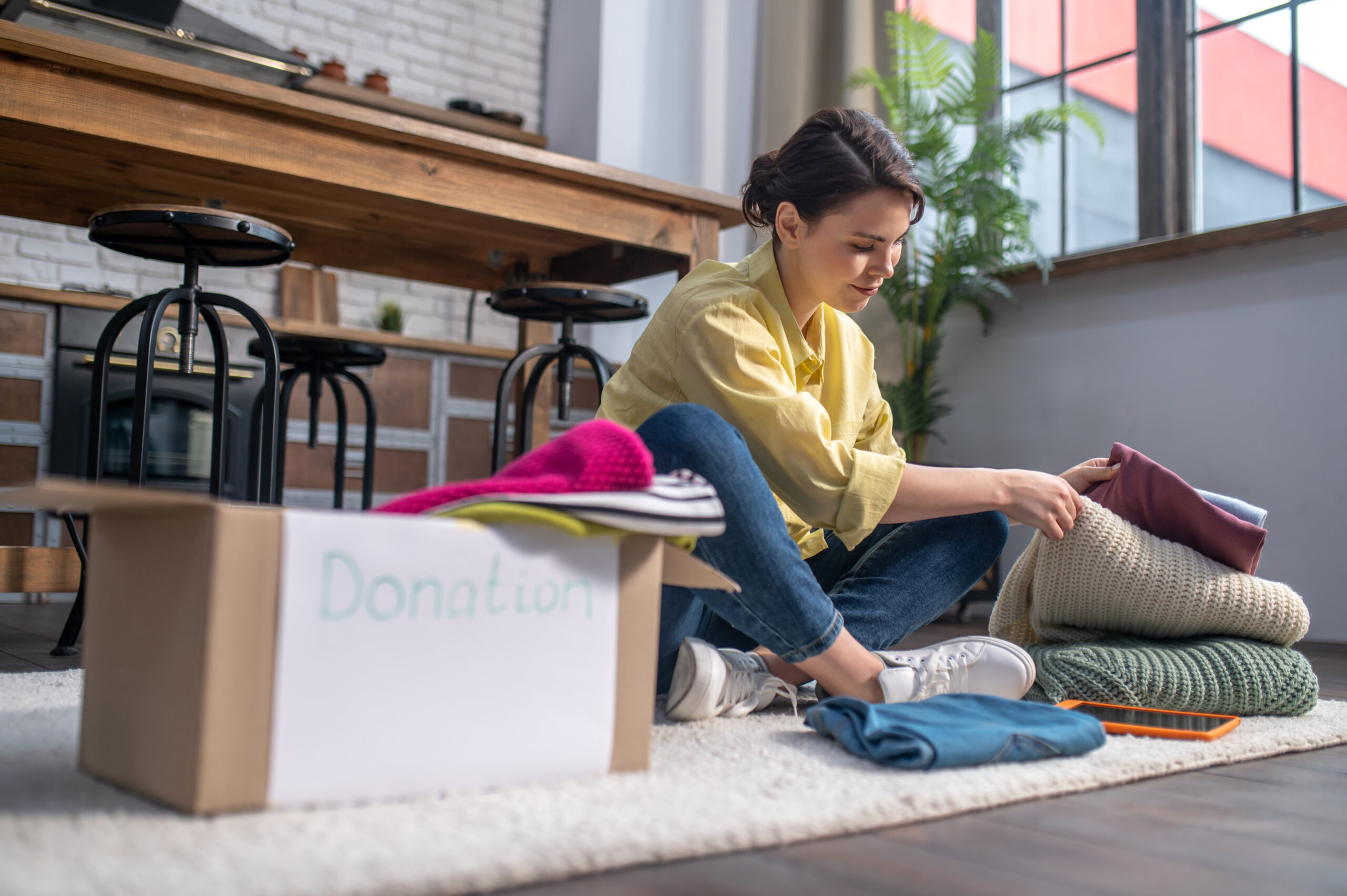 Young woman spring cleaning by sorting items to donate