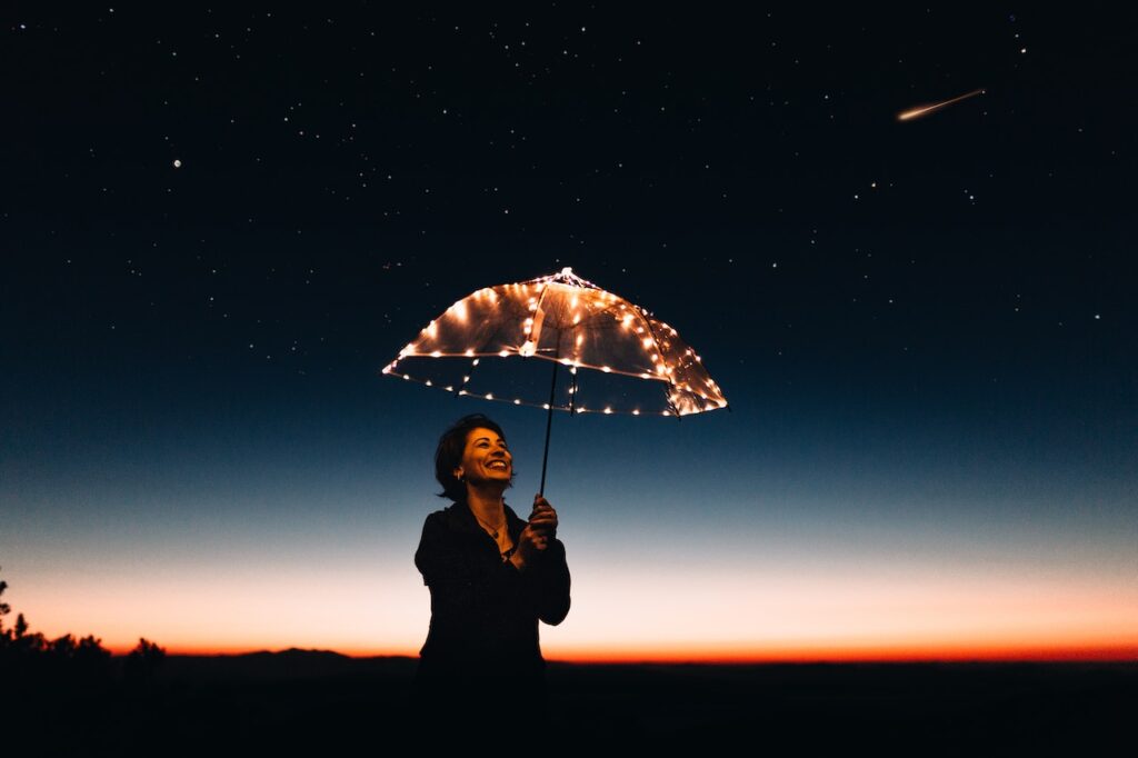 Smiling woman in the dark holding a lighted umbrella