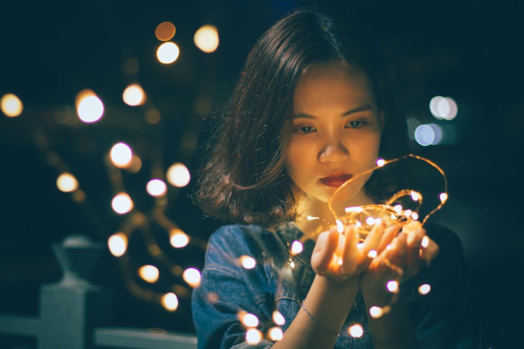 Woman staring at christmas lights in her hand looking sad