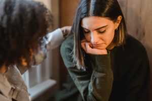 depressed looking woman being consoled by friend